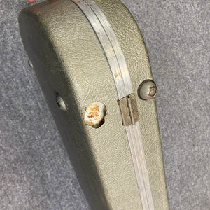 A Charvel Model 4 HSS Red electric guitar in its original hard shell case (OHSC) with a green textured finish, metal hinge, visible dents, and rust on the lid, displayed against a gray background.