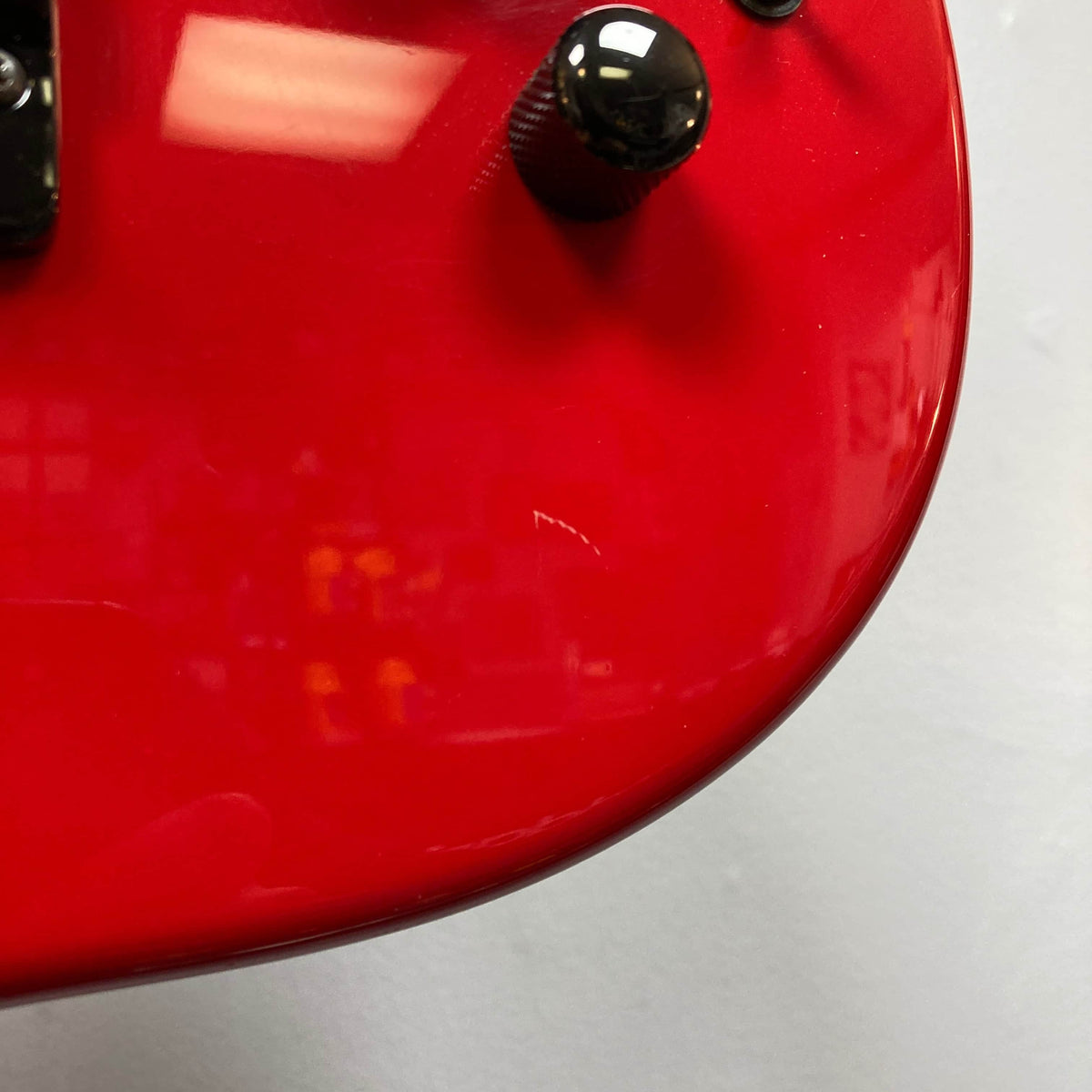 Close-up of the Charvel Model 4 HSS Red w/OHSC Consign by Charvel, featuring a glossy body, black knob, and reflected overhead lights that highlight its HSS pickup configuration.