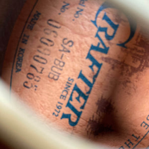 Close-up of a stamped label inside a used Crafter SA-BUB Acoustic Electric Guitar, showing "CRAFTER SINCE 1972," model "SA-BUB," serial "UC090785," and "MADE IN KOREA" in blue—perfect for onstage performance.