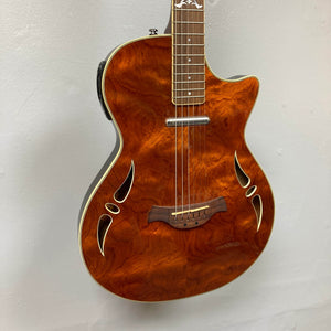 The Crafter SA-BUB Acoustic Electric Guitar Used Consign features a glossy, figured wood finish, dual sound holes by the bridge, and white edge binding—ideal for stage-ready performance against any backdrop.