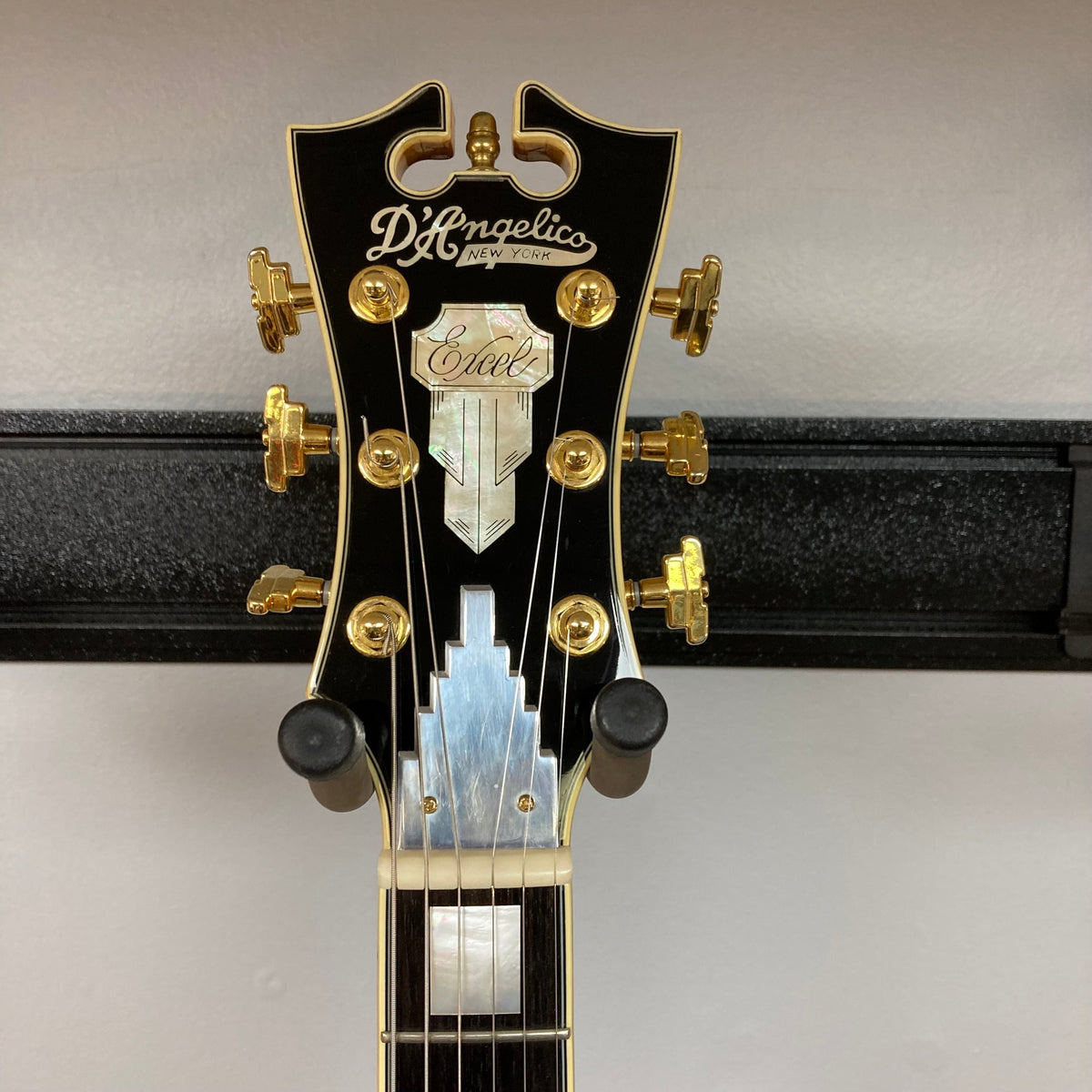 D&#39;Angelico Excel DC Semi-hollowbody Vintage Natural guitar on a stand, showcasing its double-cutaway design and semi-hollow construction with gold hardware.