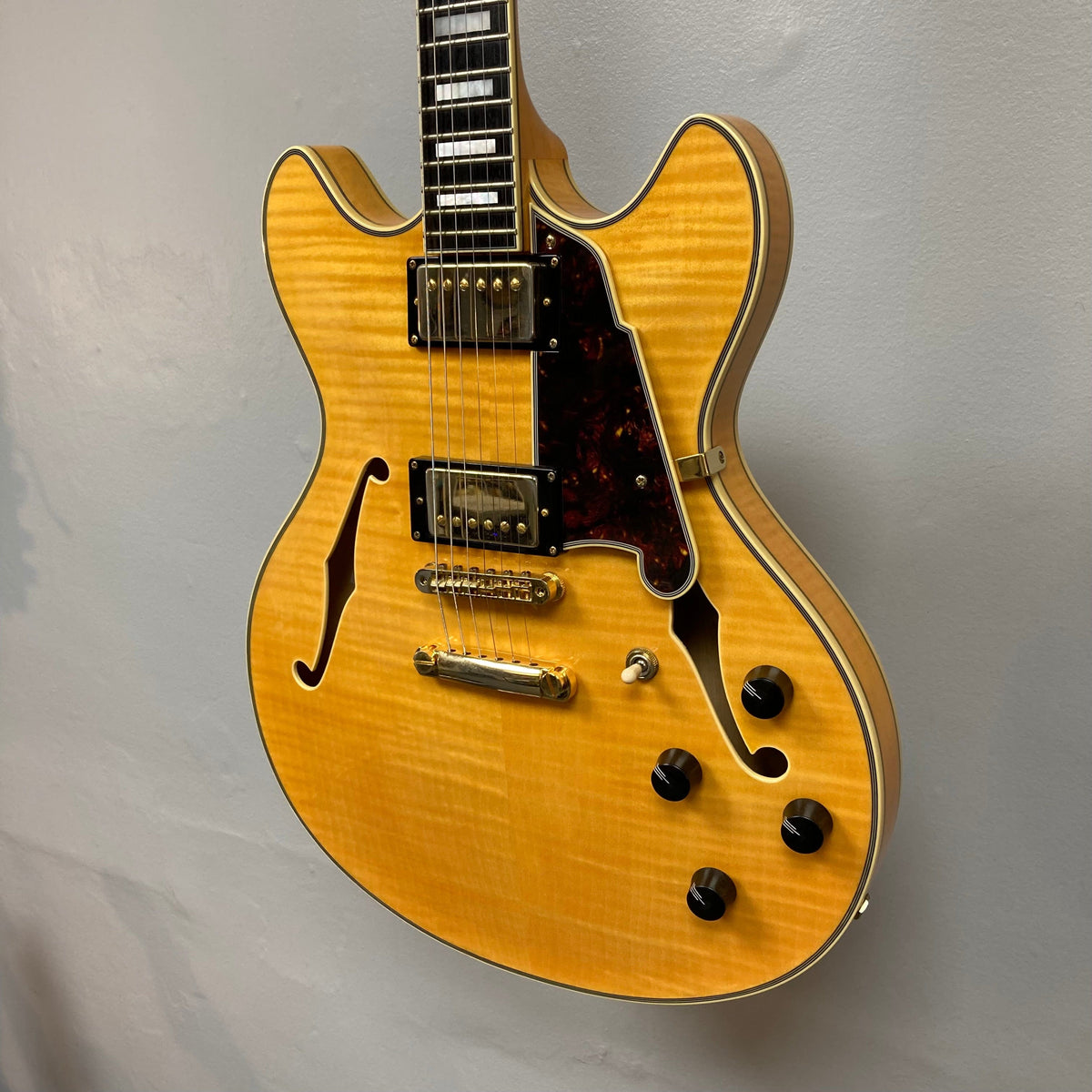 Close-up of the D&#39;Angelico Excel DC semi-hollowbody guitar, showcasing its strings, bridge, and double-cutaway design.