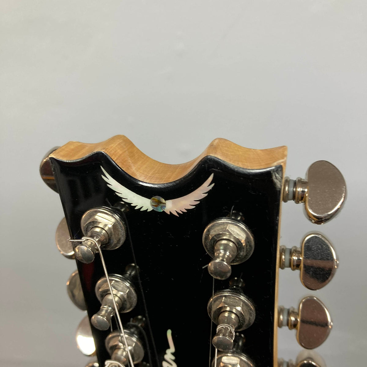 Close-up of a Dean Boca Trans Amber Burst 12 String headstock with twelve tuning pegs and an inlaid white bird design, ideal for fans of the semi hollow body guitar style. Includes gigbag.
