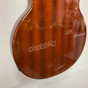 Close-up of the back of a Dean Boca Trans Amber Burst 12 String guitar showing a scratch on the wood finish and reflected text.