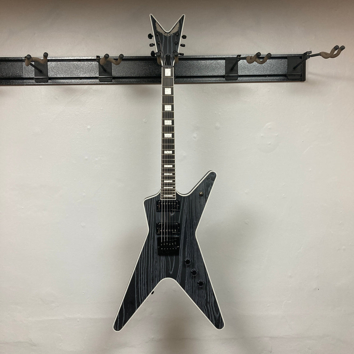 Dean Custom Run #16 ML Sandblasted Grey guitar hanging, showcasing its iconic ML design, Evertune bridge, and Fishman pickups. Limited edition, perfect for enthusiasts and collectors.