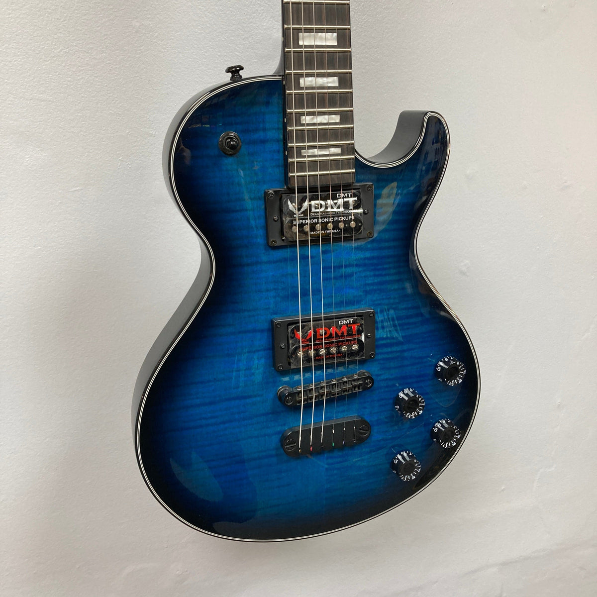 Dean Thoroughbred John Connolly Trans Blueburst electric guitar displayed against a white wall, showcasing its premium build and stunning design.