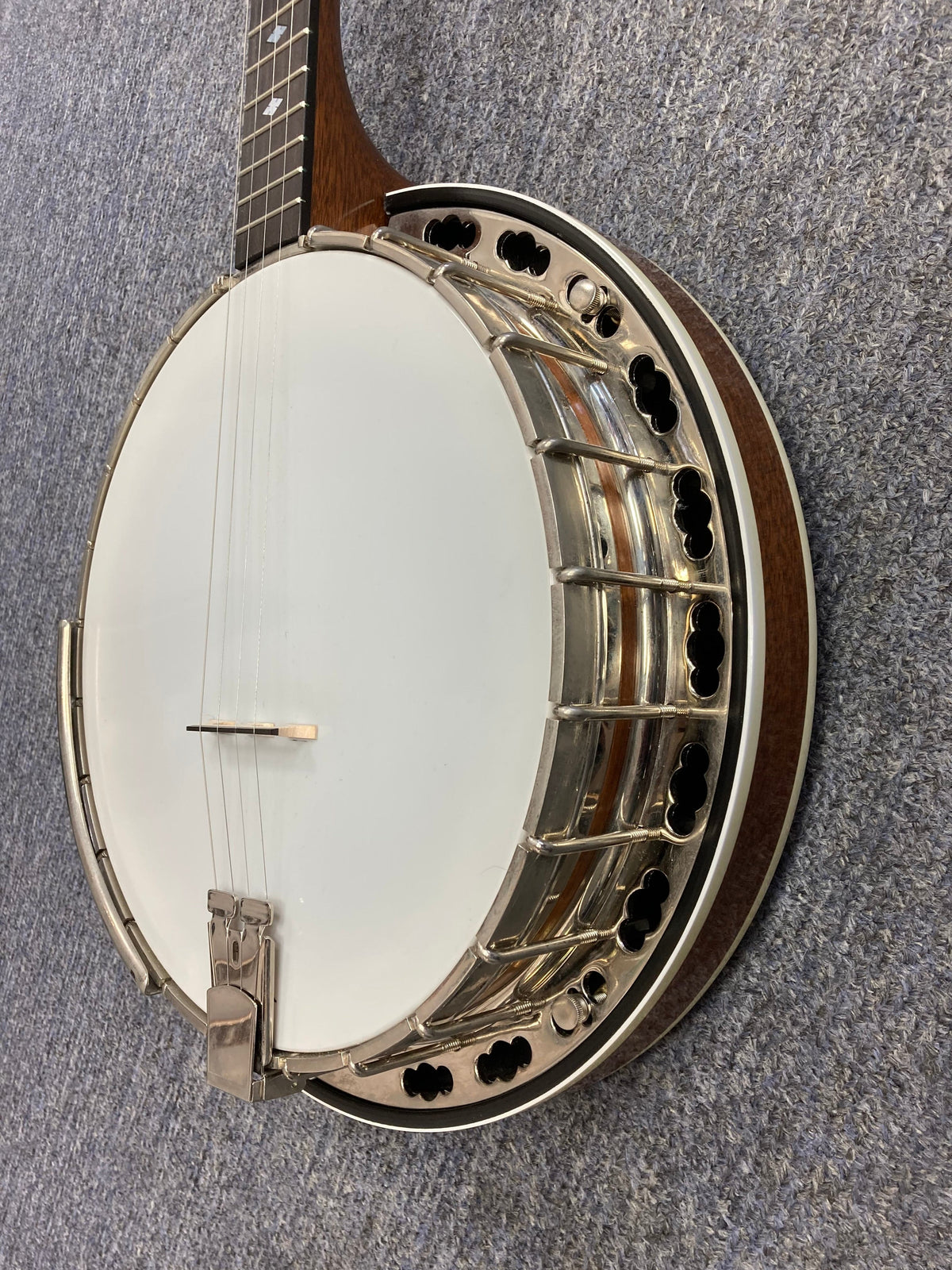 Deering Deluxe 4-String Banjo on a carpet, showcasing its intricate metal and wooden components.