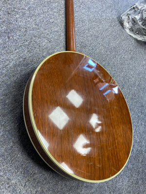 Deering Deluxe 4-String Banjo, close-up showcasing its wooden body and strings, highlighting its guitar-like tuning for easy playability.