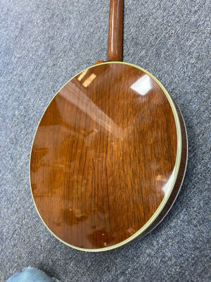 Close-up of the Deering Deluxe 4-String Banjo, highlighting its wooden body and strings.