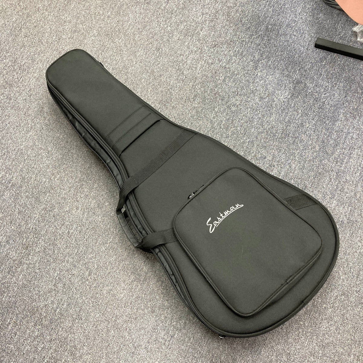 Black Eastman E1D Dreadnought Natural w/Gigbag Used acoustic guitar gig bag with a zippered front pocket and a branded logo.