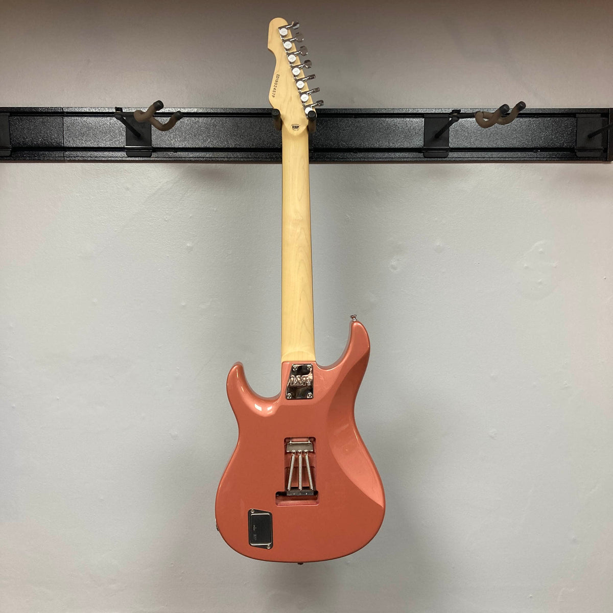 An Edwards E-SN7-194MF Mikio Fujioka Signature seven-string guitar in Burgundy Mist, made by Edwards, hangs on a black wall mount and is pictured from the back against a plain light-colored wall.