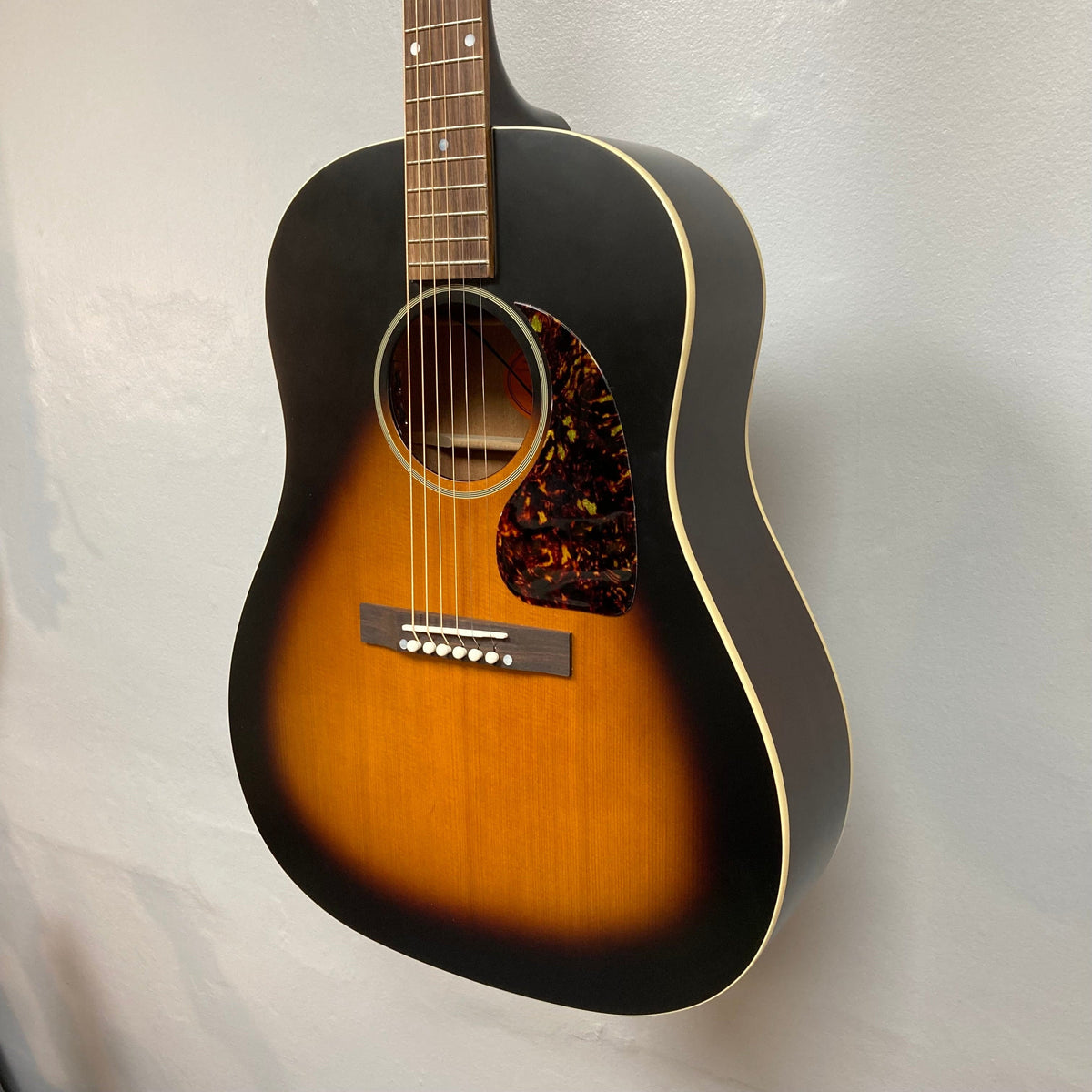 Epiphone 1942 Banner J-45 Vintage Sunburst acoustic guitar displayed on a wall, highlighting its iconic design and craftsmanship.