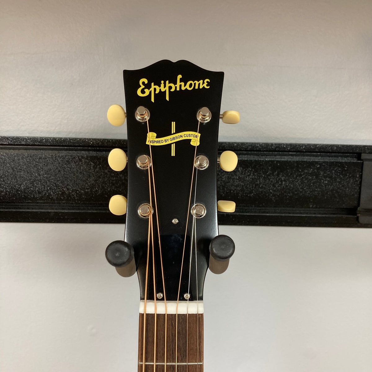 Epiphone 1942 Banner J-45 Vintage Sunburst acoustic guitar displayed on a wall, highlighting its strings, headstock, and detailed craftsmanship.