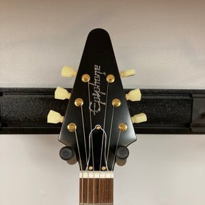 Epiphone 1958 Korina Flying V guitar on display, showcasing its solid Korina body, Indian laurel fretboard, and gold hardware, includes a hardshell case.