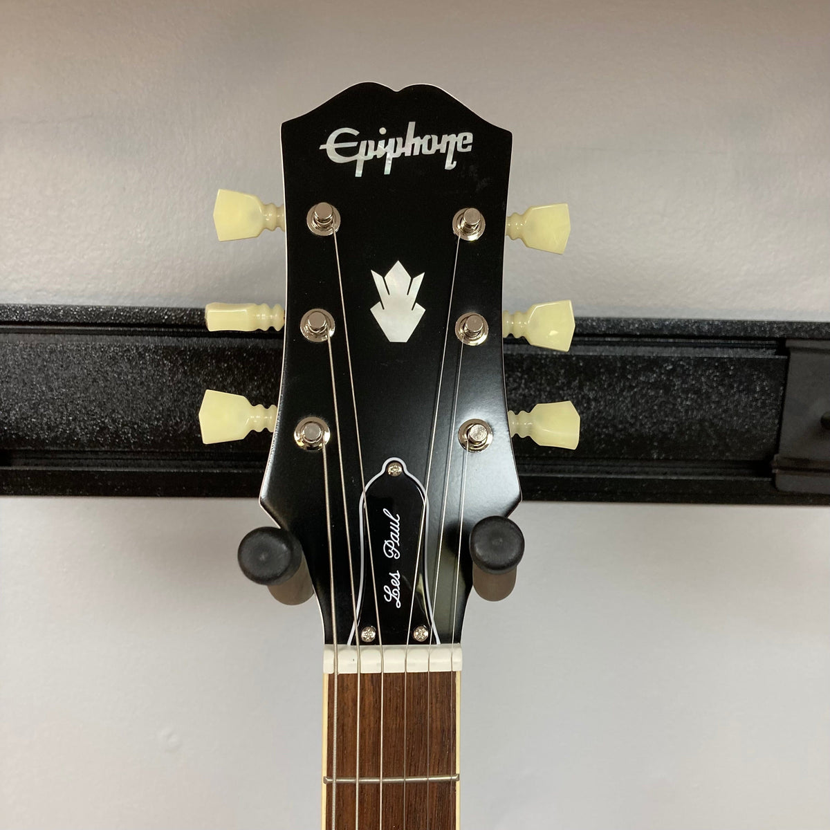 Epiphone 1961 Les Paul SG Standard Aged Classic White on a stand, showcasing its distinctive double-cutaway body and six-string design.