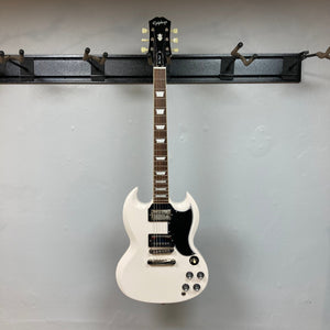 Epiphone 1961 Les Paul SG Standard Aged Classic White displayed on a hook, showcasing its iconic design and craftsmanship.