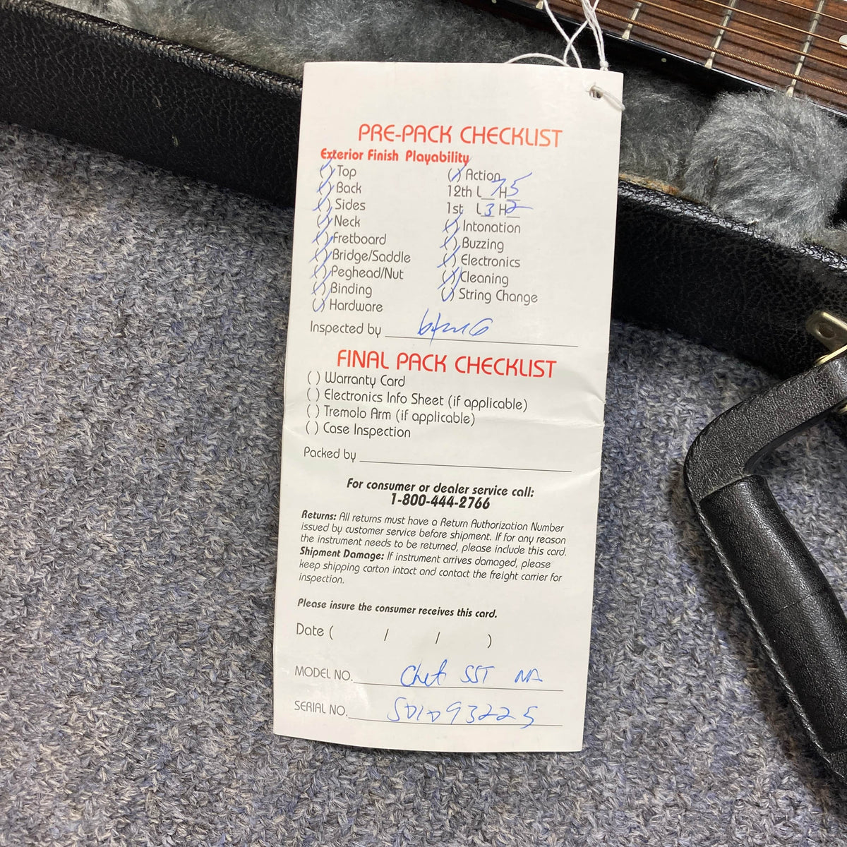 A pre-pack checklist tag for the Epiphone Chet Atkins SST Studio Natural Korea w/Hard Case shows "OK," date "1/5/23," and model info, with boxes checked for exterior finish and final inspection. Tag rests on a gray surface near the hard case.