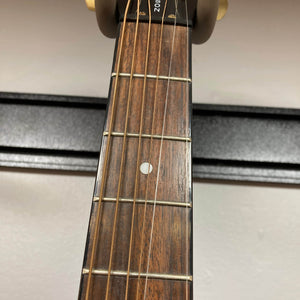 Close-up of the Epiphone Chet Atkins SST Studio Natural Korea guitar neck, featuring six strings, metal frets, a circular fifth-fret inlay, and wooden fingerboard; its feedback-resistant acoustic-electric design appears in the background.