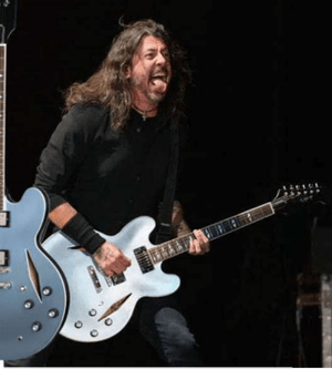 Man playing an Epiphone Dave Grohl DG-335 guitar on stage, showcasing its design and craftsmanship.