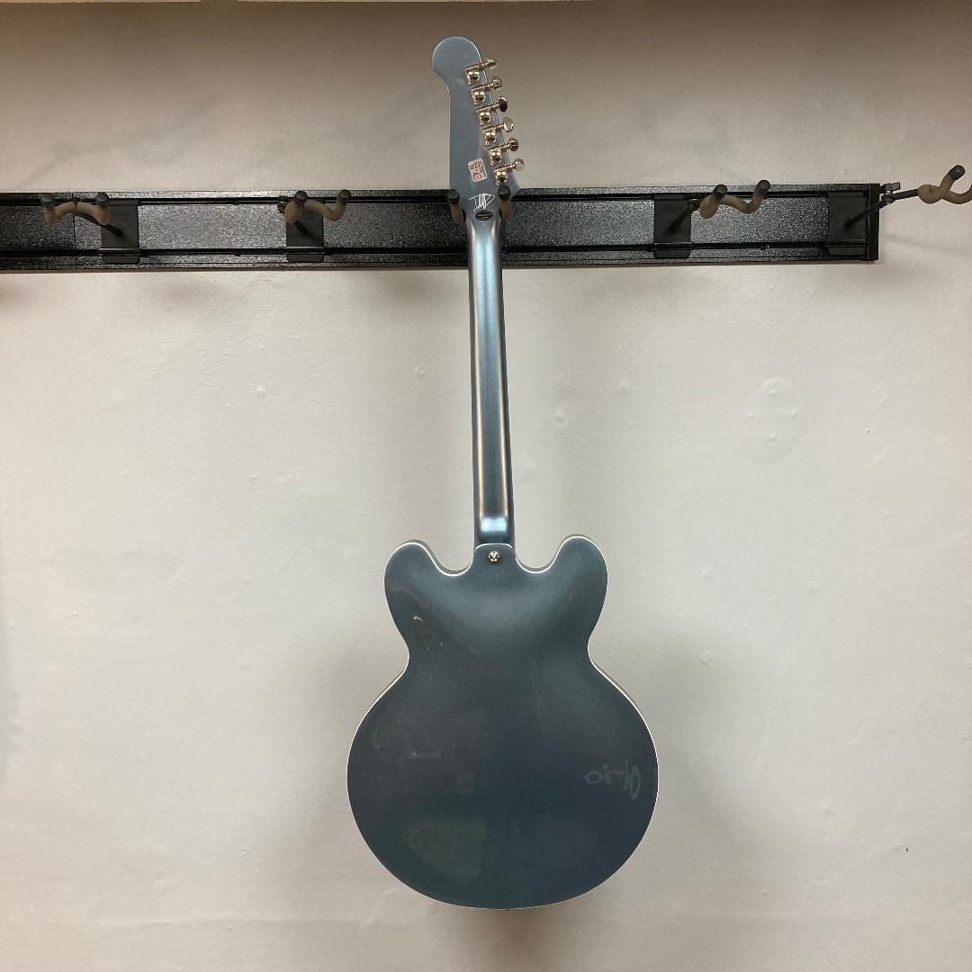 Epiphone Dave Grohl DG-335 guitar hanging on a wall, showcasing its intricate features including split diamond inlays and bound diamond F-holes.