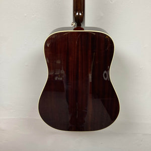 A rear view of the Epiphone Hummingbird Studio Antique Natural w/Gigbag by Epiphone displays its glossy dark wood back with cream binding, photographed against a plain white wall.