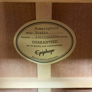 Label inside the wooden guitar reads: "Epiphone Hummingbird Studio Faded Cherry Sunburst w/Gigbag is guaranteed for quality and craftsmanship. Fishman Sonitone pickup. Handcrafted in Indonesia.