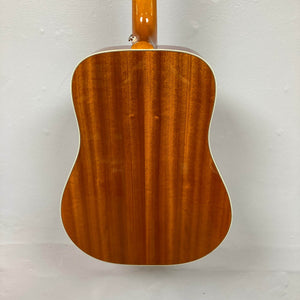A close-up of the back of an Epiphone Hummingbird Studio Faded Cherry Sunburst acoustic guitar by Epiphone, showing its glossy finish and vertical wood grain, photographed against a plain white wall.