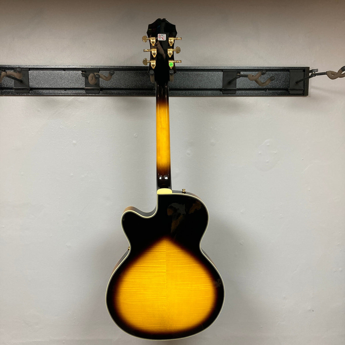 Epiphone Joe Pass Emperor II Vintage Sunburst guitar displayed on a wall, highlighting its intricate design and gold knobs.