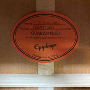 The orange label inside this small-bodied acoustic reads: "Epiphone L-00 Standard Vintage Sunburst w/Gigbag, GUARANTEED for quality and craftsmanship, Handcrafted in China.