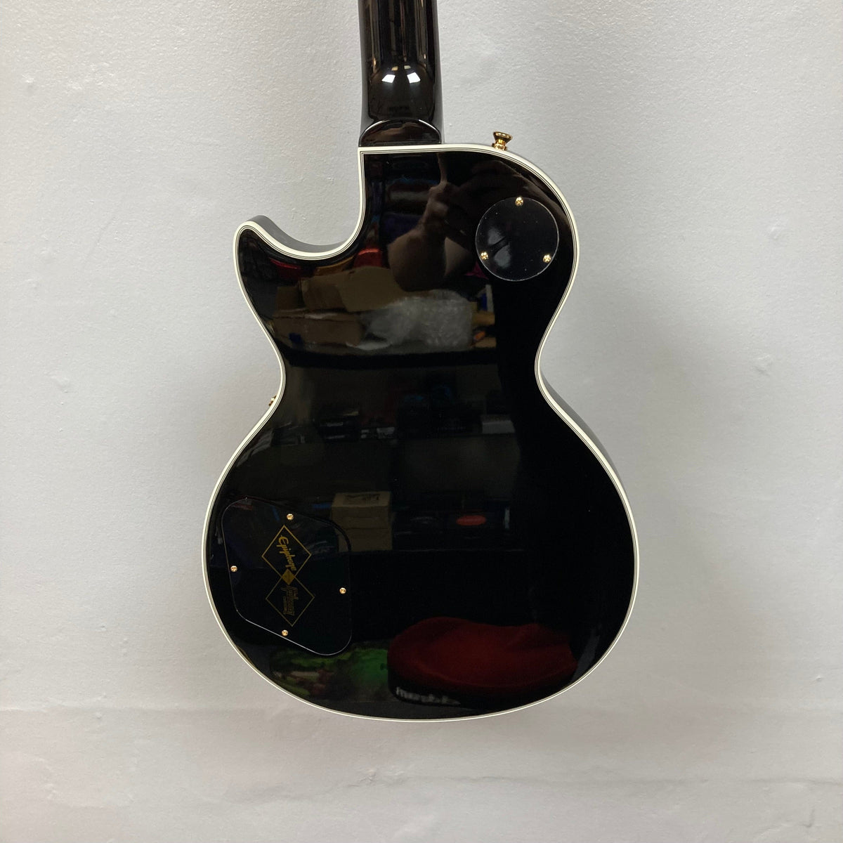 Epiphone Les Paul Custom Inspired by Gibson Ebony w/Case, featuring a black electric guitar with a mahogany body and maple top, displayed on a white surface.