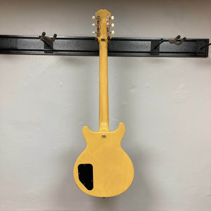 An Epiphone Les Paul Special Double Cut TV Yellow electric guitar with gigbag hangs on a wall rack, displayed from the back with its electronics cover plate visible.
