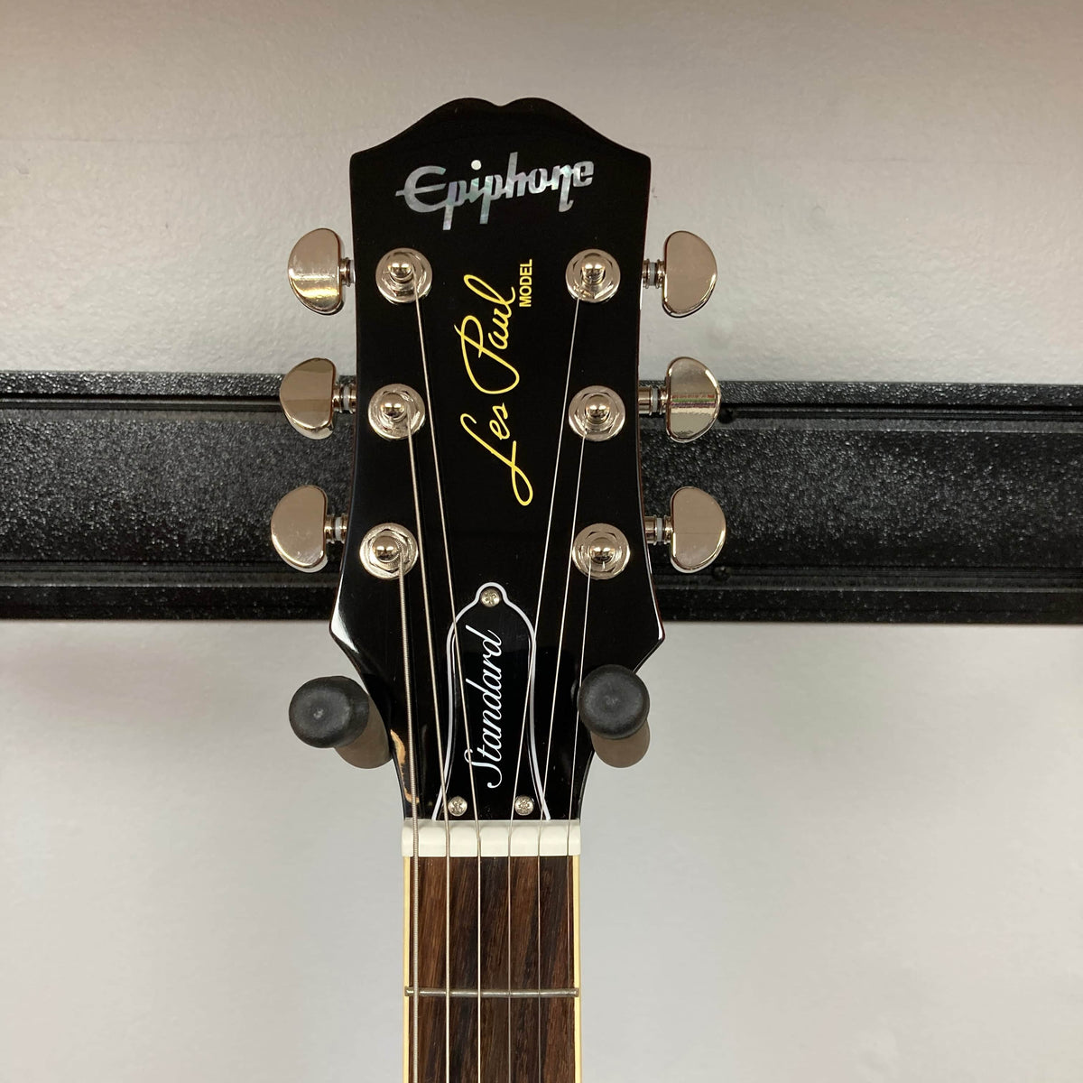 Close-up of the Epiphone Les Paul Standard 60s Figured Iced Tea Burst headstock, showing tuning pegs and logos against a plain background, highlights its classic design. Includes gigbag.