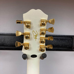 Close-up of the back of an Epiphone Matt Heafy Les Paul Custom Origins, Bone White headstock with gold tuning pegs, serial number, signature, and a "Hand Crafted in China" label.
