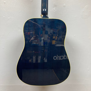 Epiphone Miranda Lambert Bluebird Studio - Bluebonnet guitar displayed on a wall, highlighting its solid spruce top and tortoise pickguard with bluebird graphic.