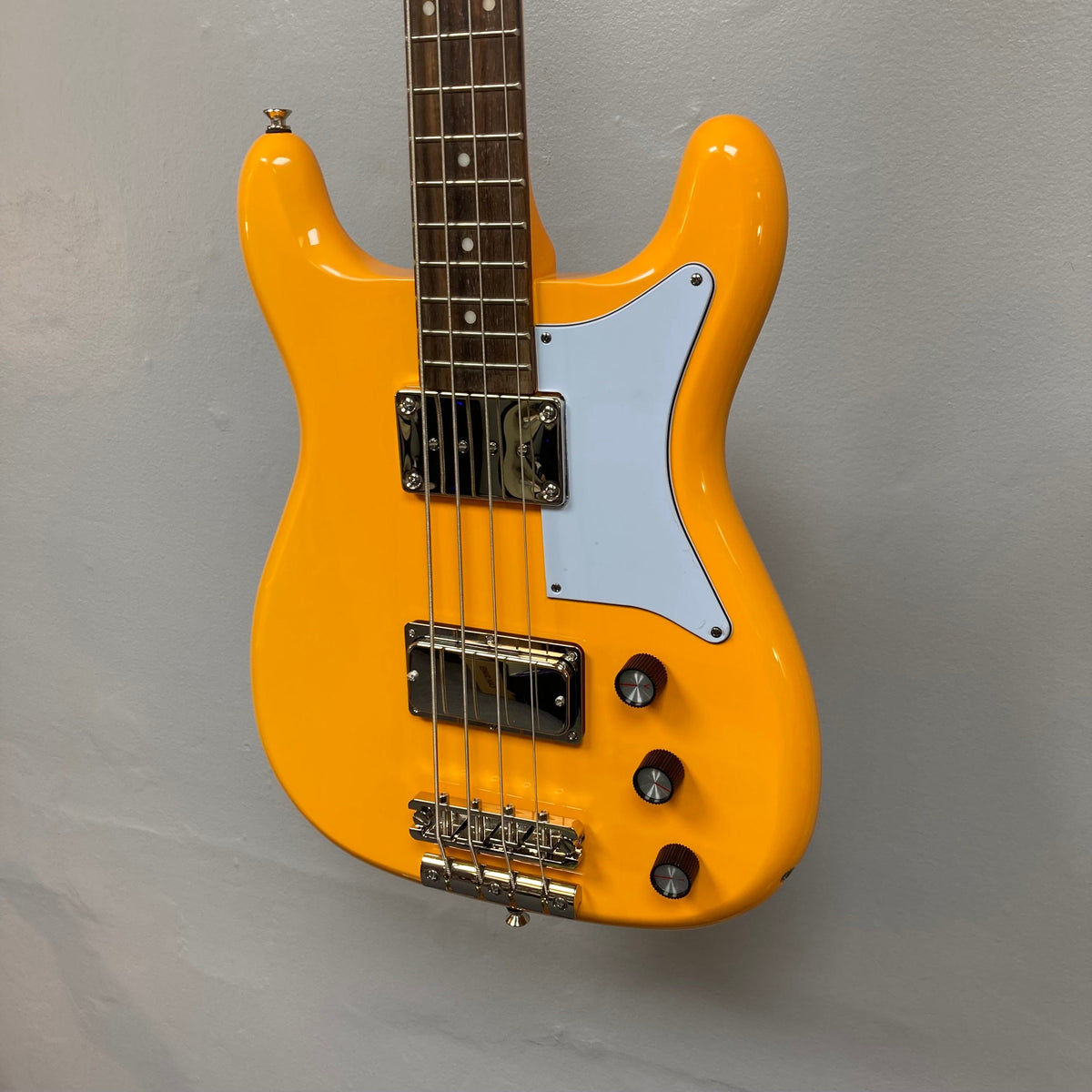 Epiphone Newport Bass California Coral, featuring a unique body shape with visible control knobs and pickups, mounted on a wall.