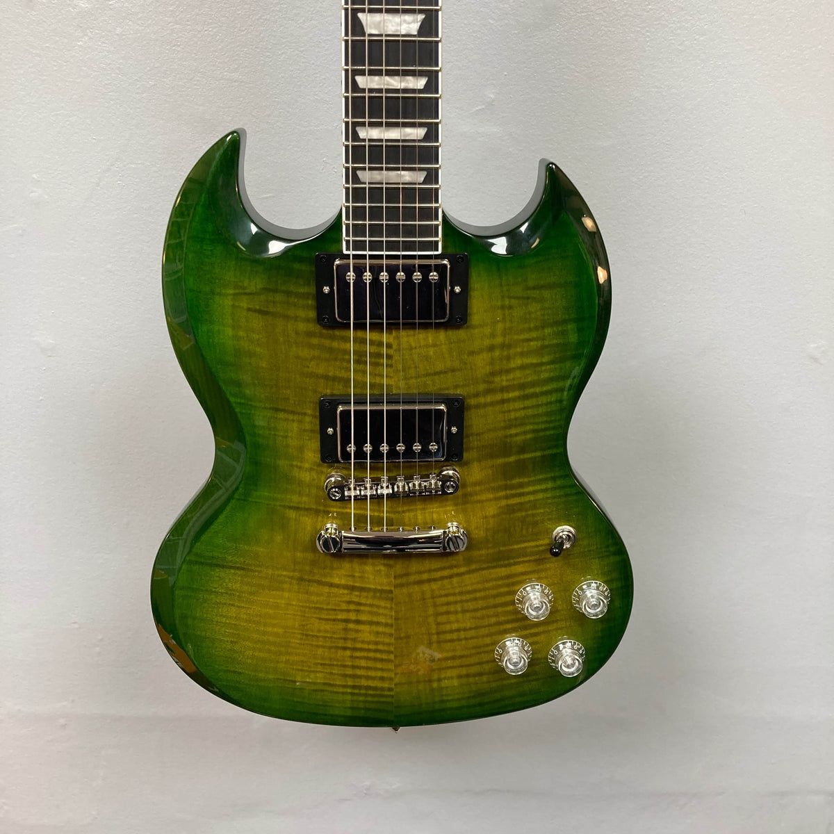 The Epiphone SG Modern Figured in Iguana Burst features a glossy finish, ProBucker humbuckers, four control knobs, a SlimTaper neck, and a double cutaway body—shown on a plain white background. Includes gig bag.