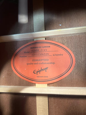 Inside the Epiphone Slash J-45 Acoustic Guitar w/Case, an orange label states: "Inspired by Gibson. Model SLASH J-45, Number 22032304529, guaranteed quality and craftsmanship. Features Shadow NanoFlex pickup. FOR EVERY STAGE.