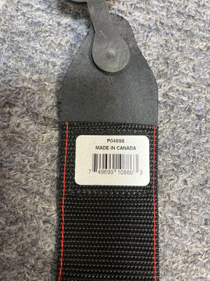 A close-up of the Ernie Ball Guitar Strap - Peace & Dove shows its black material with red stitching and a white label marked "P04698 MADE IN CANADA," resting on a textured gray surface.