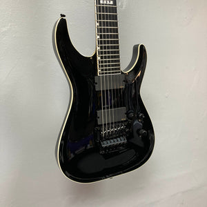 An ESP E-II Horizon FR-7 Black w/Case seven-string electric guitar with a Floyd Rose bridge and double-cutaway body hangs on a light-colored wall.