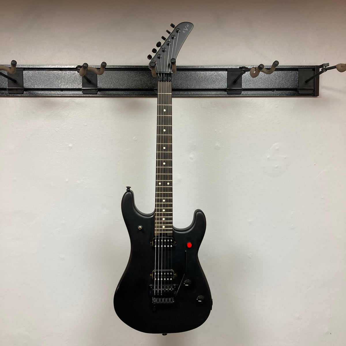 EVH 5150 Standard Stealth Black Used electric guitar displayed on a wall, featuring distinctive detailing and design.