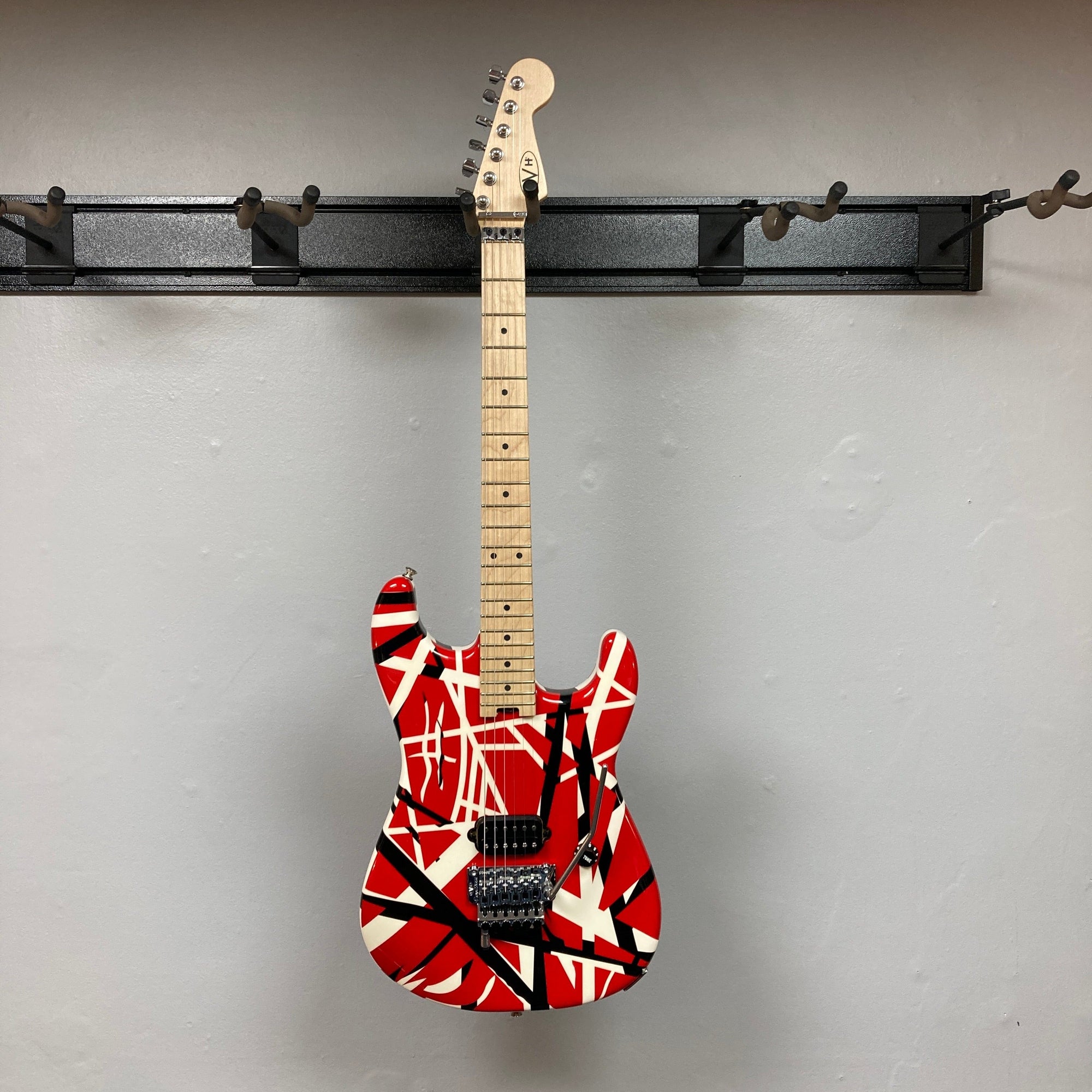 EVH Striped Series electric guitar with distinctive red, black, and white stripes, showcasing close-ups of its body and strings.