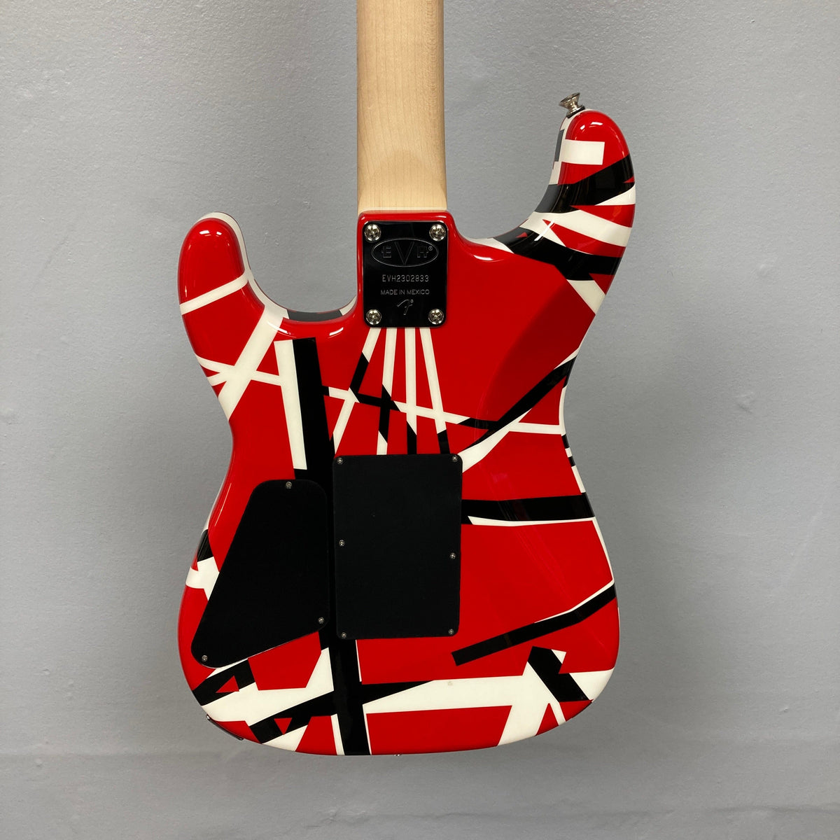 EVH Striped Series electric guitar in red, black, and white, showcasing its unique striped design and precise craftsmanship, ideal for guitar enthusiasts.