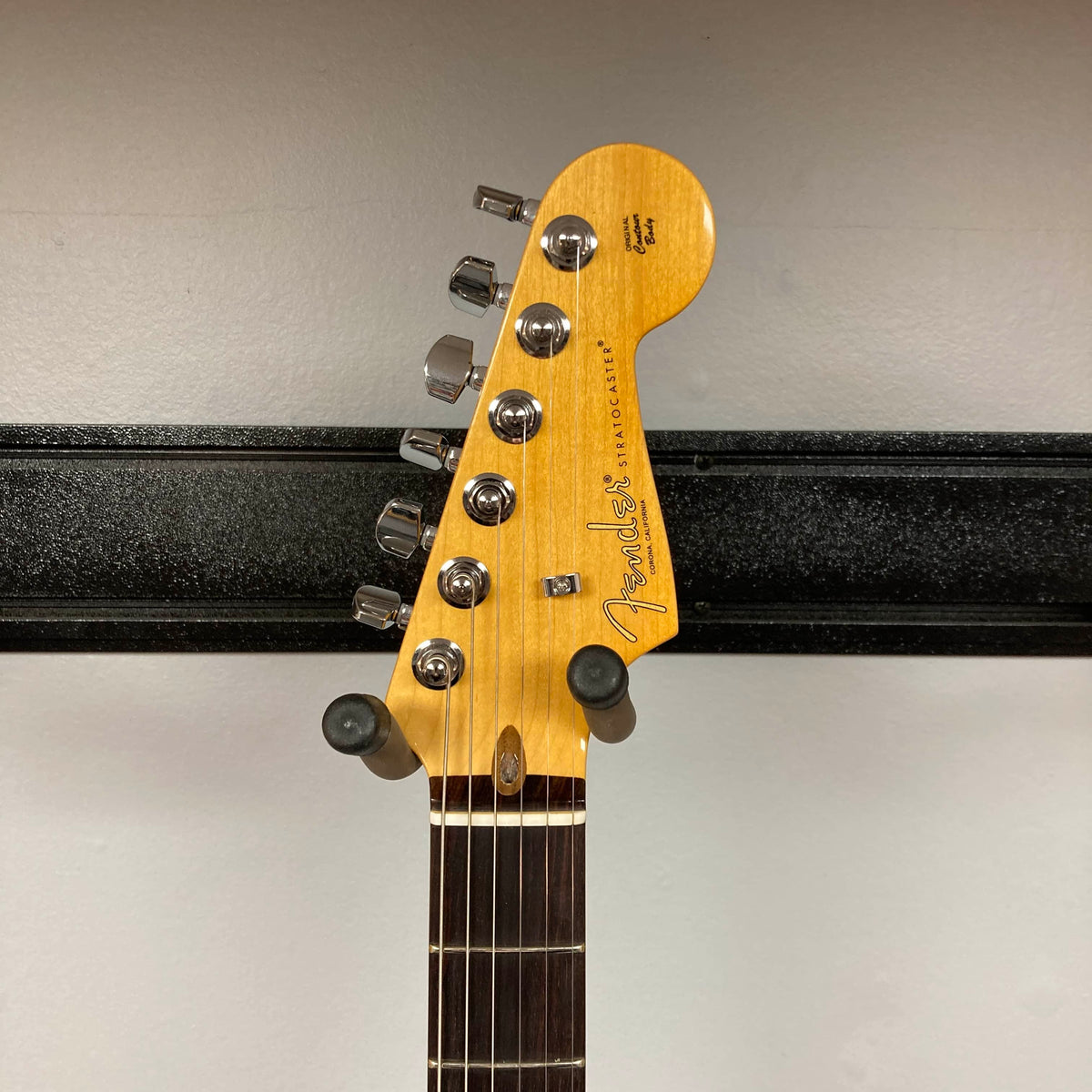 Headstock of a Fender Telecaster electric guitar on a wall hanger, displaying tuning pegs, logo, and fretboard—similar in style to the HSS layout on the Fender American Professional II Stratocaster HSS in Dark Night w/Case.