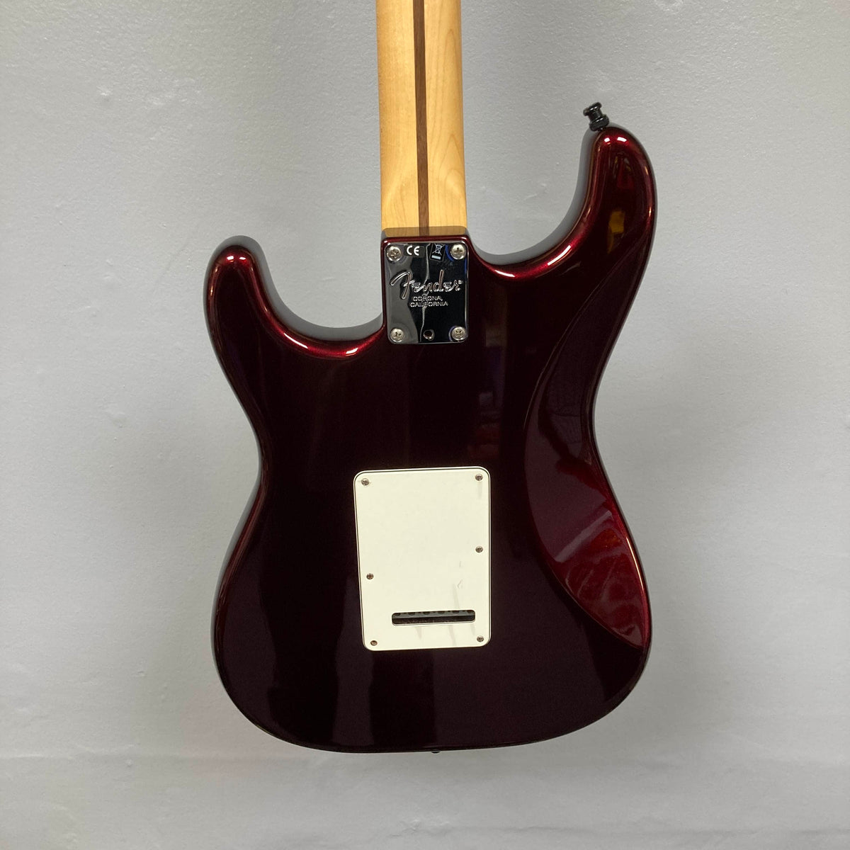 Back view of a Bordeaux Metallic Fender American Standard Strat upgraded Gilmour EMG DC-20 electric guitar (used) against a light gray wall, showing the neck joint, back plate, and no strings attached.
