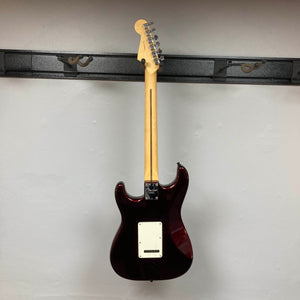 A striking Fender American Standard Strat upgraded Gilmour EMG DC-20 electric guitar in stunning Bordeaux Metallic is displayed on a wall-mounted rack, shown from the back with its neck pointing upward and the body downward. Outfitted with high-performance Gilmour EMG DC-20 pickups, this used Fender model comes complete with a case.