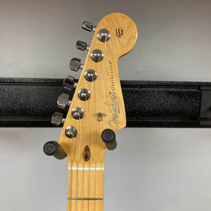 Here’s a rewritten sentence using your product data: Close-up of a Fender American Standard Strat upgraded Gilmour EMG DC-20 in striking Bordeaux Metallic, showcasing six tuning pegs, string guides, and the classic Fender logo. This used guitar comes with a case and is displayed on a wall hanger against a gray background.