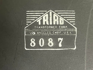 Logo for Triad Transformer Corp, address "Los Angeles, Calif., U.S.A." and number "8087" on a dark surface, as seen on vintage Fender 1957 Bassman 5F6 Narrow Panel 40-Watt 4x10" Guitar Combo w/Flight Case.