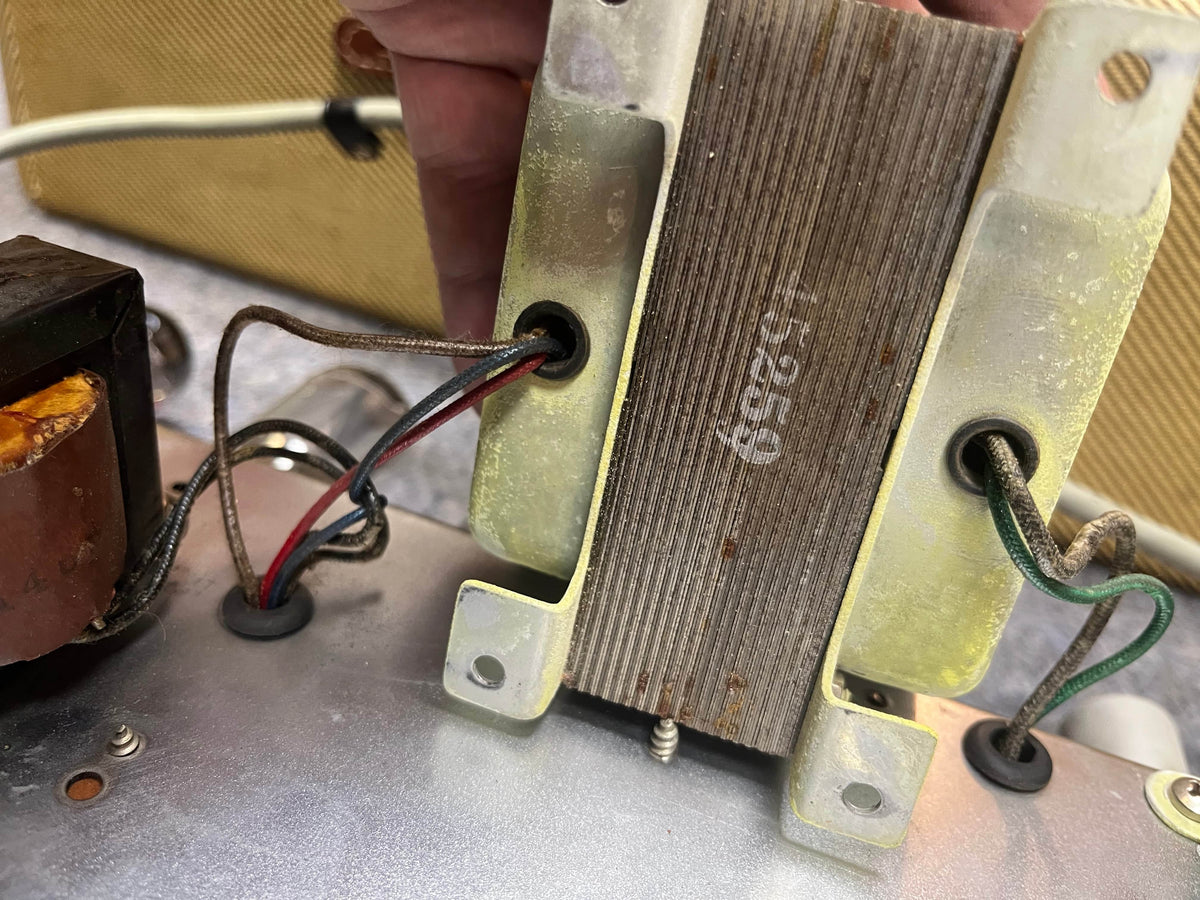 Close-up of a hand holding a transformer labeled “45259,” wired and mounted inside a 1957 Fender Bassman 5F6 Narrow Panel 40-Watt 4x10" Guitar Combo by Fender.