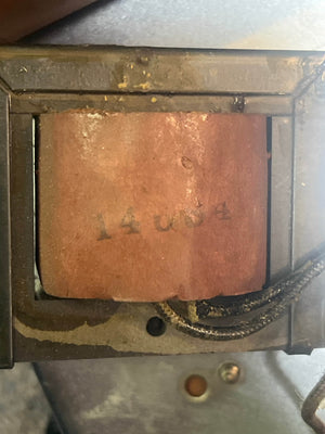 Close-up of a metal component from a 1957 Fender Bassman 5F6 Narrow Panel 40-Watt 4x10" Guitar Combo w/Flight Case, showing a faded reddish label with "14084" and two black wires attached at the bottom. Brand: Fender.