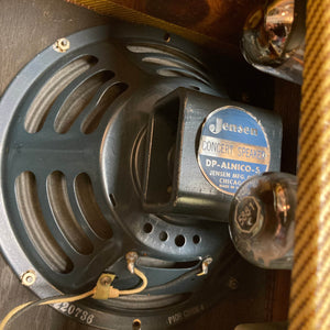 Close-up of a Jensen Concert Speaker DP-ALNICO-5 inside a 1957 Fender Bassman 5F6 Narrow Panel 40-Watt 4x10" Guitar Combo, highlighting the label, wiring, and part of the amplifier's striped fabric covering.